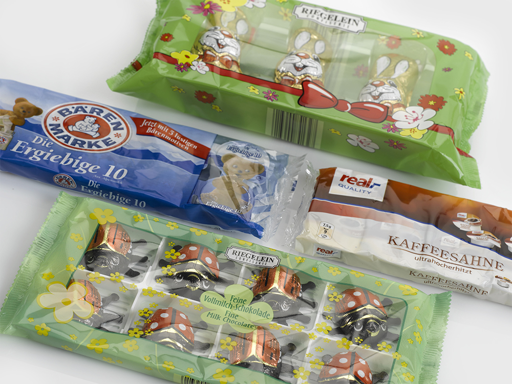 Abbildung von verpackten Schokoladenfiguren und verpackter Kaffeesahne